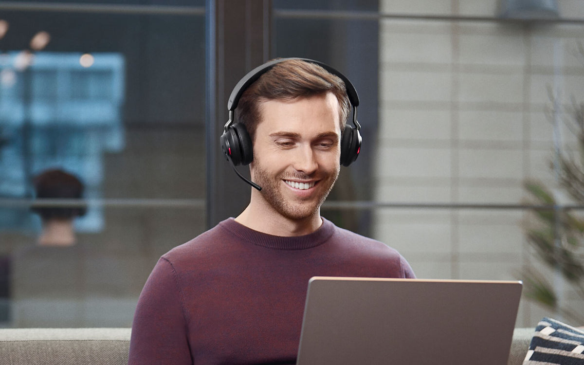 Man wearing a Jabra Evolve2 65 headset on a call at his laptop