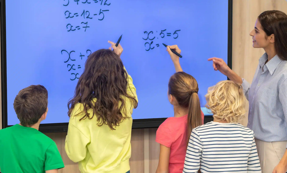 Pupils and a teacher writing maths on a OneScreen interactive display at the same time