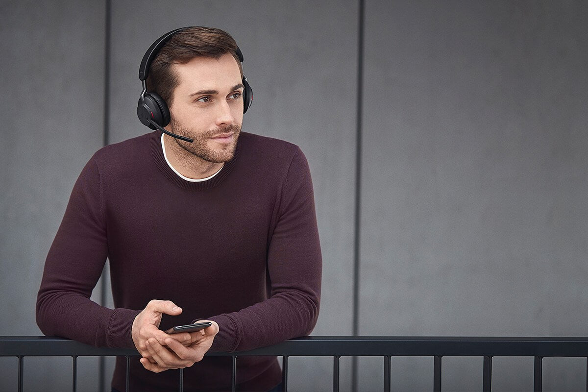 Man wearing a Jabra Evolve2 65 headset and holding a phone