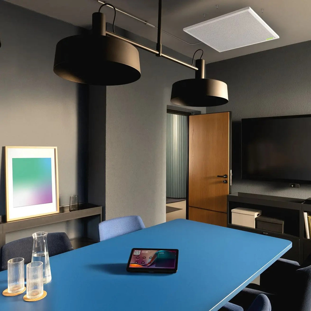 Meeting room with a Shure MXA902 ceiling array above the table and a wall display