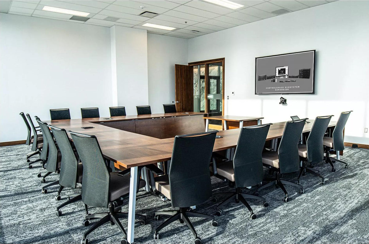 Conference room with a U-shaped table, ceiling loudspeakers and a wall display