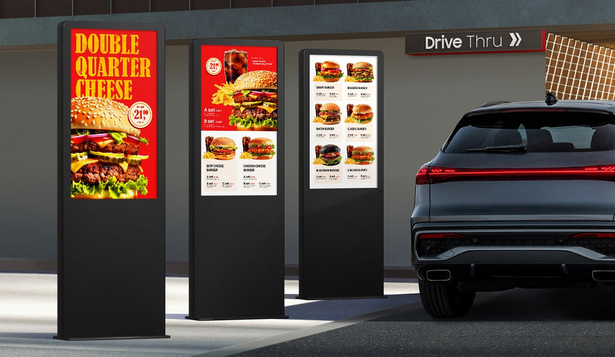 Three Samsung OHDX outdoor displays as drive-thru menu boards beside a car