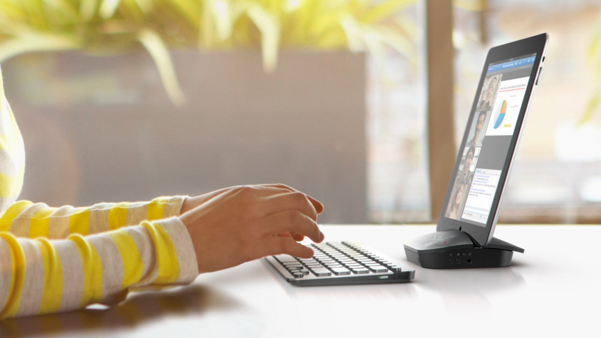 Tablet in the stand of a Logitech P710e speakerphone on a desk during a call
