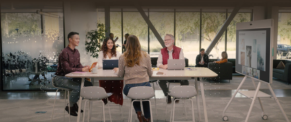 Team meeting at a table beside a Logitech Rally Board 65 on a mobile cart