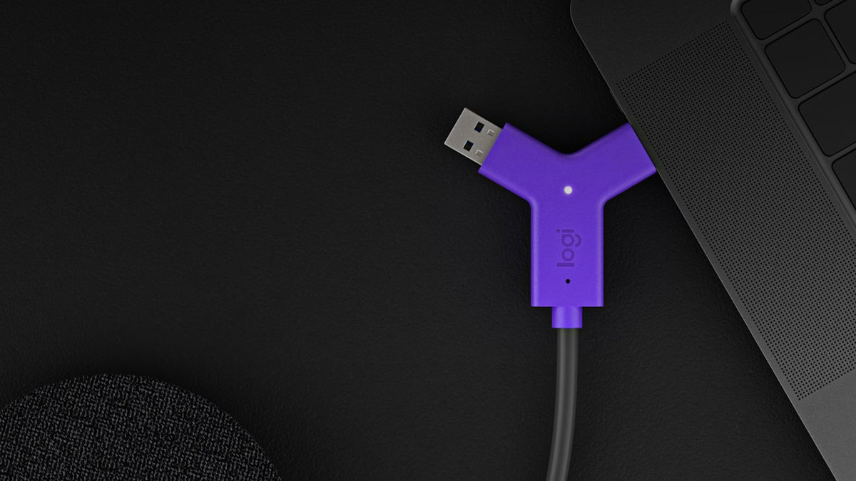 Logitech Swytch connector with USB-A and USB-C plugs next to a laptop